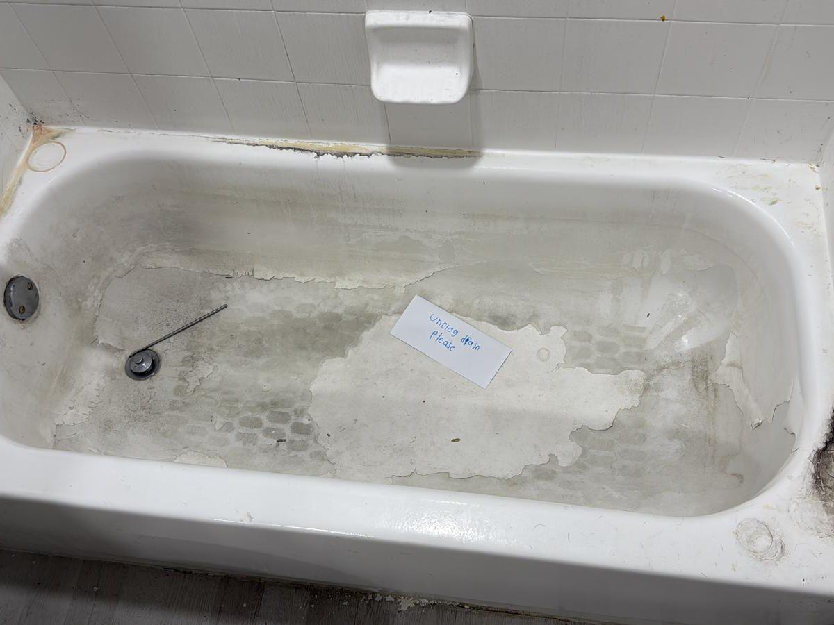 Old bathtub with stained surface and mildew at the edges
